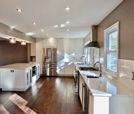 Crafstman kitchen remodeling, Ikea cabinets. - In this picture gallery, we see a kitchen remodeling example emphasizing that you don’t have to spend a fortune to renovate a sizable kitchen. By choosing Ikea kitchen cabinets with a medium-priced Ikea kitchen door, you can save but still have a gorgeous and elegant kitchen. From a small dining room and a medium size kitchen, we created a large airy gorgeous kitchen with an oversized island. We used a few Ikea kitchen glass doors on the island to emphasize the pretty china glass. We designed the kitchen with a 32” granite coated Franke main sink and a small prep sink next to the bar area close to the French doors that lead to the deck. We chose a white quartz countertop with subtle veining named Satuario.