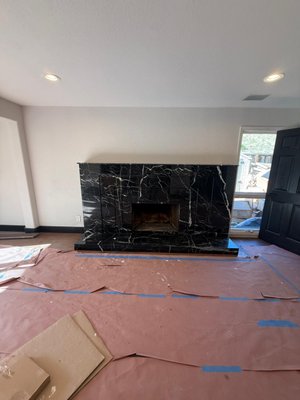 Modern Fireplace Transformation - This fireplace transformation was completed from start to finish by our team. We began by removing the existing mantel, brick surround, and fireplace insert before rebuilding the entire structure with a new custom frame to achieve the updated design. Once the framing was complete, we installed the proper backing for the large format porcelain slabs, carefully laid out each piece to keep the veining continuous, and finished all edges for a clean, seamless appearance. Every step of the project, from demolition and framing to fabrication, installation, and the final finish work, was completed by our crew, resulting in a modern fireplace that completely changed the look and feel of the living room.