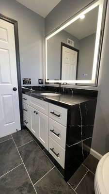 Bathroom remodel - This bathroom remodel focused on creating a relaxing and functional space centered around a new bathtub. The old fixtures were removed and replaced with updated, modern selections. A sleek alcove bathtub was installed, surrounded by custom tile work for a clean and polished look. New plumbing fixtures in a black matte finish complement the tub and coordinate with the updated vanity and lighting. A new single-sink vanity with ample storage and a quartz countertop was added, along with a large LED mirror light. The floor was redone with durable, water-resistant porcelain tile, and fresh paint and trim completed the transformation. The result is a warm, inviting bathroom that balances comfort and style. Bathroom remodel - This bathroom remodel focused on creating a relaxing and functional space centered around a new bathtub. The old fixtures were removed and replaced with updated, modern selections. A sleek alcove bathtub was installed, surrounded by custom tile work for a clean and polished look. New plumbing fixtures in a black matte finish complement the tub and coordinate with the updated vanity and lighting. A new single-sink vanity with ample storage and a quartz countertop was added, along with a large LED mirror light. The floor was redone with durable, water-resistant porcelain tile, and fresh paint and trim completed the transformation. The result is a warm, inviting bathroom that balances comfort and style.