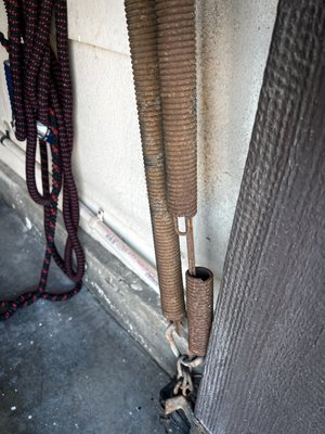 Broken One-Piece Door Extension Springs - This customer had an old, rusted, extension spring fail on their one-piece tilt-up style garage door.
One-piece garage doors remain in use and are still manufactured upon request even today. Although they operate differently from contemporary sectional doors, many of the same principles apply. Most notably, these doors also feature a counterbalance system. While sectional doors utilize torsion springs, one-piece doors employ extension springs to achieve balance and functionality.
Extension springs are responsible for counterbalancing the weight of the garage door, making it easier to open and close. They stretch and contract with the door's movement, and their integrity is vital for the door's functionality. The One-Piece Garage Door Extension Springs are specifically designed for certain weight range of doors, and though replacement can be straightforward, adjustment rarely is.
There are several reasons why one may want to, or need to, replace their one-piece tilt-up garage door springs. Common indicators include:
• Visible rust or corrosion
• Broken coils or gaps in the spring
• Uneven stretching or sagging
• Difficulty in opening or closing the garage door
Replacing worn-out and broken One-Piece Extension Springs is an essential task for maintaining the functionality and safety of your garage door. Just because the door is old, doesn’t necessarily mean it needs to be replaced though. Call us today if you have an older one-piece tilt-up garage door that could use some attention. Broken One-Piece Door Extension Springs - This customer had an old, rusted, extension spring fail on their one-piece tilt-up style garage door.
One-piece garage doors remain in use and are still manufactured upon request even today. Although they operate differently from contemporary sectional doors, many of the same principles apply. Most notably, these doors also feature a counterbalance system. While sectional doors utilize torsion springs, one-piece doors employ extension springs to achieve balance and functionality.
Extension springs are responsible for counterbalancing the weight of the garage door, making it easier to open and close. They stretch and contract with the door's movement, and their integrity is vital for the door's functionality. The One-Piece Garage Door Extension Springs are specifically designed for certain weight range of doors, and though replacement can be straightforward, adjustment rarely is.
There are several reasons why one may want to, or need to, replace their one-piece tilt-up garage door springs. Common indicators include:
• Visible rust or corrosion
• Broken coils or gaps in the spring
• Uneven stretching or sagging
• Difficulty in opening or closing the garage door
Replacing worn-out and broken One-Piece Extension Springs is an essential task for maintaining the functionality and safety of your garage door. Just because the door is old, doesn’t necessarily mean it needs to be replaced though. Call us today if you have an older one-piece tilt-up garage door that could use some attention.