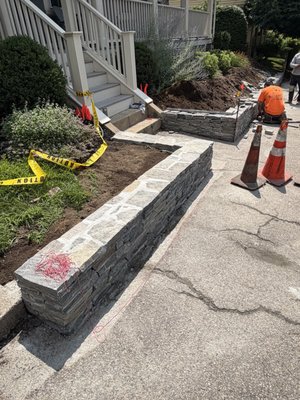 Medford Wall with thin wall stones - Our client wanted a new wall to create separation from the street that blends both the look of a natural stone wall with their recently renovated home and the historic style of their neighborhood. We are one of the few  landscapers who routinely model our stone and planting projects using AI tools to make our customer's visions a reality.