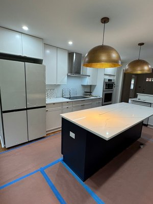 Winter Kitchen Remodel - This complete kitchen remodel was designed to create a modern, functional, and elegant space while maximizing efficiency and flow. The project features a full layout upgrade with a large custom island that serves as the centerpiece of the kitchen, offering additional prep space, seating potential, and built-in electrical outlets for everyday convenience.
New shaker-style cabinetry was installed throughout, providing clean lines and ample storage. A two-tone cabinet design adds depth and contrast, paired with sleek modern hardware for a refined finish. Quartz countertops were installed on all surfaces, including the island, delivering durability, low maintenance, and a bright, upscale appearance.
The kitchen includes updated stainless steel appliances, a built-in wall oven and microwave combination, and a modern range hood that blends seamlessly with the cabinetry. A stylish hexagon tile backsplash was installed to add texture and visual interest while maintaining a timeless look.
Lighting was fully upgraded with recessed LED ceiling lights and statement pendant fixtures above the island, creating both functional task lighting and warm ambiance. Plumbing and electrical components were updated as needed to meet modern standards and enhance usability.
Throughout the project, surfaces were carefully protected during construction, and attention was given to clean lines, symmetry, and craftsmanship. The result is a bright, open, and contemporary kitchen built for everyday living and entertaining. Winter Kitchen Remodel - This complete kitchen remodel was designed to create a modern, functional, and elegant space while maximizing efficiency and flow. The project features a full layout upgrade with a large custom island that serves as the centerpiece of the kitchen, offering additional prep space, seating potential, and built-in electrical outlets for everyday convenience.
New shaker-style cabinetry was installed throughout, providing clean lines and ample storage. A two-tone cabinet design adds depth and contrast, paired with sleek modern hardware for a refined finish. Quartz countertops were installed on all surfaces, including the island, delivering durability, low maintenance, and a bright, upscale appearance.
The kitchen includes updated stainless steel appliances, a built-in wall oven and microwave combination, and a modern range hood that blends seamlessly with the cabinetry. A stylish hexagon tile backsplash was installed to add texture and visual interest while maintaining a timeless look.
Lighting was fully upgraded with recessed LED ceiling lights and statement pendant fixtures above the island, creating both functional task lighting and warm ambiance. Plumbing and electrical components were updated as needed to meet modern standards and enhance usability.
Throughout the project, surfaces were carefully protected during construction, and attention was given to clean lines, symmetry, and craftsmanship. The result is a bright, open, and contemporary kitchen built for everyday living and entertaining.