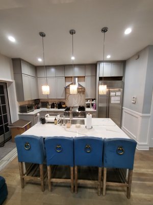 Amazing Kitchen Remodel Project – Modern Luxury Design - As part of a AAA Construction full gut rehab, this stunning kitchen remodel showcases a sleek and sophisticated modern design with high-end finishes and thoughtful details. The space features custom gray shaker-style luxury cabinets that provide both timeless elegance and ample storage. Extending to the ceiling, these cabinets enhance the kitchen’s clean lines and maximize functionality.

The countertops are a striking white Calacatta quartz, offering a seamless and opulent surface that beautifully complements the cabinetry. The waterfall-edge island serves as a breathtaking focal point, adding both style and practicality, perfect for casual dining and entertaining.

Adding to the ambiance are crystal pendant lights, elegantly suspended over the island, casting a refined glow that enhances the kitchen’s sophisticated aesthetic. Throughout the space, 4" recessed can lights provide balanced illumination, ensuring a bright and welcoming environment.

The backsplash, also in Calacatta quartz, extends from the countertops for a cohesive and luxurious look, while stainless steel finishes on appliances and fixtures bring a contemporary edge to the design. The transformation is completed with custom gray hardwood floors, which add warmth and contrast, tying the entire space together in a perfect blend of modern elegance and functional luxury.