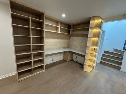 White Oak Open Workspace with LED Lights - This custom-built corner workspace perfectly combines functionality and aesthetics. The design features open bookshelves offering generous storage capacity and easy access to essentials. A broad work zone provides space for productivity, while the L-shaped layout maximizes every inch of the room.
The corner shelves, beautifully curved and enhanced with warm LED lighting, add a refined touch and create a cozy, inviting atmosphere. The entire setup is crafted in a white oak style wood-textured finish, giving the space a modern yet timeless look — ideal for both work and inspiration. White Oak Open Workspace with LED Lights - This custom-built corner workspace perfectly combines functionality and aesthetics. The design features open bookshelves offering generous storage capacity and easy access to essentials. A broad work zone provides space for productivity, while the L-shaped layout maximizes every inch of the room.
The corner shelves, beautifully curved and enhanced with warm LED lighting, add a refined touch and create a cozy, inviting atmosphere. The entire setup is crafted in a white oak style wood-textured finish, giving the space a modern yet timeless look — ideal for both work and inspiration.