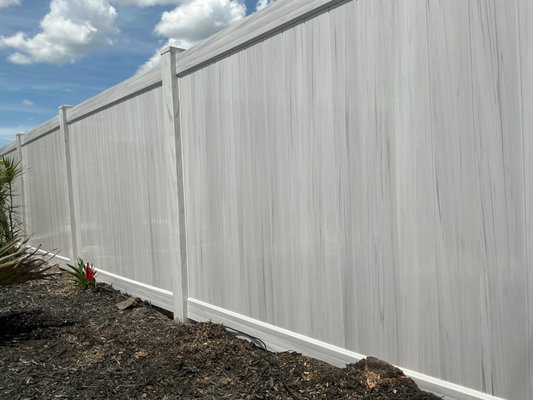 Aspen Grey Vinyl - This is an example of Aspen Grey Vinyl. This vinyl is part of the Wood Grain series of color options. They also have weathered cedar, chestnut brown, and more! These panels are 8ft wide and come with bottom and top metal rail supports and 3 picket stiffeners per section to keep this fence nice and strong for years to come!