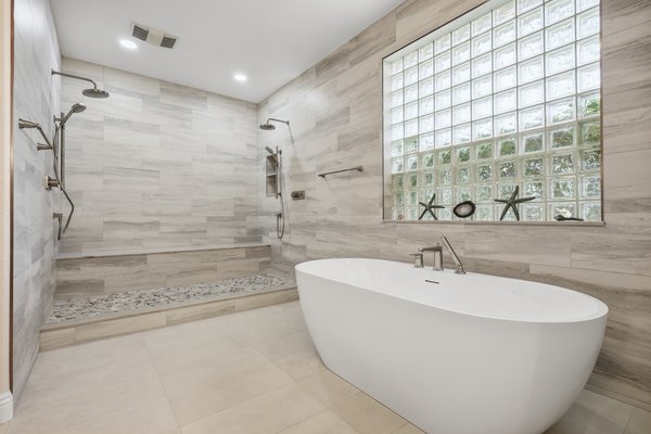 Sandstone - This project focused on transforming the primary bathroom into a bright, spa-inspired retreat with an emphasis on clean lines, functionality, and premium materials. We reconfigured the layout to create a more open and cohesive space while improving flow between the bathroom, sauna, and adjacent areas.
The walk-in shower features a Kohler Anthem thermostatic valve system for precise temperature control, paired with a linear drain for a seamless, modern look. Large-format tile and a pebble shower floor were used to enhance durability while maintaining a calm, natural aesthetic.
Custom cabinetry provides generous, well-organized storage, keeping the space uncluttered and practical for everyday use. A freestanding soaking tub anchors the room and reinforces the spa-like feel, complemented by soft gray tones and subtle coastal influences throughout.
As part of the remodel, we also reconfigured the primary bedroom closet entrance, improving functionality and better integrating the space into the overall layout.
The result is a refined, timeless master bathroom designed for comfort, relaxation, and long-term performance. Sandstone - This project focused on transforming the primary bathroom into a bright, spa-inspired retreat with an emphasis on clean lines, functionality, and premium materials. We reconfigured the layout to create a more open and cohesive space while improving flow between the bathroom, sauna, and adjacent areas.
The walk-in shower features a Kohler Anthem thermostatic valve system for precise temperature control, paired with a linear drain for a seamless, modern look. Large-format tile and a pebble shower floor were used to enhance durability while maintaining a calm, natural aesthetic.
Custom cabinetry provides generous, well-organized storage, keeping the space uncluttered and practical for everyday use. A freestanding soaking tub anchors the room and reinforces the spa-like feel, complemented by soft gray tones and subtle coastal influences throughout.
As part of the remodel, we also reconfigured the primary bedroom closet entrance, improving functionality and better integrating the space into the overall layout.
The result is a refined, timeless master bathroom designed for comfort, relaxation, and long-term performance.