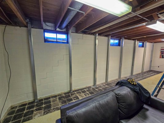 Bowing Wall Repair - Cedar Falls, IA - For this project in Cedar Falls, we worked with a homeowner who was concerned about a basement wall that had begun to bow inward over time. To address the structural pressure and stop the movement before it led to a more serious failure, we installed the PowerBrace™ system. 

These zinc-plated steel beams were custom-fitted to the height of the basement and secured to the floor and floor joists, creating a permanent reinforcement that stabilizes the foundation without the need for exterior digging.

One of the best features of this setup is the adjustable bracket at the top of each beam. It allows for the system to be tightened during dry seasons, which can actually help push the wall back toward its original position over the coming years. By choosing this interior solution, we were able to provide the homeowner with long-term peace of mind and a much more stable foundation, all while keeping their yard and landscaping completely untouched.