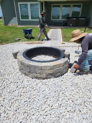 Backyard Walkway & Fire Pit Lounge – Airbnb Enhancement - We transformed this Airbnb backyard into a welcoming retreat with a custom-designed walkway and fire pit area. The path features white limestone borders filled with crushed white limestone and natural stepping stones, guiding guests to a cozy circular fire pit built from stacked concrete blocks. The fire pit is finished with lava rock for a clean, modern look and better heat retention—perfect for evening gatherings. The upgrade adds both aesthetic value and functionality, enhancing the overall guest experience. Backyard Walkway & Fire Pit Lounge – Airbnb Enhancement - We transformed this Airbnb backyard into a welcoming retreat with a custom-designed walkway and fire pit area. The path features white limestone borders filled with crushed white limestone and natural stepping stones, guiding guests to a cozy circular fire pit built from stacked concrete blocks. The fire pit is finished with lava rock for a clean, modern look and better heat retention—perfect for evening gatherings. The upgrade adds both aesthetic value and functionality, enhancing the overall guest experience.