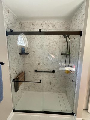 Shower Update - In this stunning remodel, we've said goodbye to the customer's outdated tub/shower and ushered in a new era of luxury. The focal point of this transformation is the installation of opulent panels that exude sophistication, complemented by the warmth of a teak foldable shower seat. The pinnacle of elegance is achieved with the addition of sliding glass doors, offering both functionality and a touch of modern style. This picture is a testament to the beauty of a bathroom reimagined with a blend of opulence and practicality, showcasing our commitment to excellence in our Yelp portfolio.