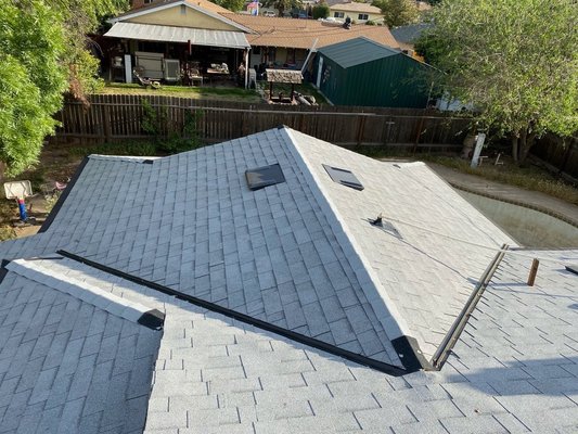 Shingle Roof Replacement — Gray Shingles - Complete reroof on a multi-plane residential roof. Final photos show a clean, uniform gray architectural shingle install with straight, consistent courses, finished valleys, and matching ridge/hip caps. Existing roof features were properly tied in, including skylights and vent/pipe penetrations, for a watertight, finished look.