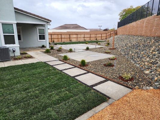 New Home Modern Backyard Install - Complete modern installation for a new home featuring a grass play area, hot tub pad, extended patio, and cost-effective cobblestone on the slope to save on retaining wall costs. New Home Modern Backyard Install - Complete modern installation for a new home featuring a grass play area, hot tub pad, extended patio, and cost-effective cobblestone on the slope to save on retaining wall costs.