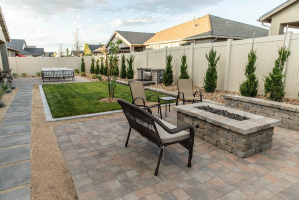 Welcoming Oasis - Making the most of a limited outdoor space
This backyard transformation involved defining outdoor living spaces to make the overall area feel larger. In the center of it all, we installed turf with a water feature along the edge, a welcome sight in the desert.
The main attraction could be the paver patio, with an inviting set of comfortable patio furniture. Or it could be the outdoor dining area and its view of the green lawn. A stepping stone walkway connects these areas to a rectangular-shaped fire pit area. Vibrant green plantings line the fences along the edges of the backyard, giving the illusion of expanded space. Welcoming Oasis - Making the most of a limited outdoor space
This backyard transformation involved defining outdoor living spaces to make the overall area feel larger. In the center of it all, we installed turf with a water feature along the edge, a welcome sight in the desert.
The main attraction could be the paver patio, with an inviting set of comfortable patio furniture. Or it could be the outdoor dining area and its view of the green lawn. A stepping stone walkway connects these areas to a rectangular-shaped fire pit area. Vibrant green plantings line the fences along the edges of the backyard, giving the illusion of expanded space.
