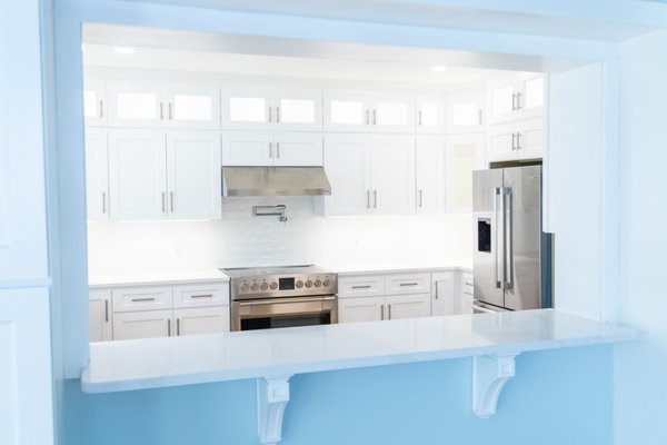 Forest Hills Kitchen Remodel - This beautiful home in Forest Hills was in need of a little TLC and a layout update.  We closed off a mudroom area with an entry to the backyard and made it an exterior storage closet.  We also took a small window above the sink and installed a wide 6' triple window to let in a cascade of daylight and open up the view to their amazing backyard.

We installed a simple, crisp white cabinetry with stacked glass cabinetry.  The cabinetry is accented by the lighting in the stacked glass and the under cabinet lighting.  An apron front fireclay sink, pot filler and hand made white subway tile complete the timeless look and provide the kitchen with understated elegance.
