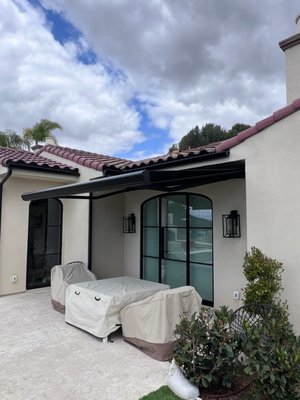 Modern Awnings - This modern awning project was designed to preserve the homeowner's beautiful Spanish aesthetic while shading her patio when outside. She adored the streamlined, valance-free design and opted for the motorized front curtain to receive additional shade while the sun sets low in the sky! Modern Awnings - This modern awning project was designed to preserve the homeowner's beautiful Spanish aesthetic while shading her patio when outside. She adored the streamlined, valance-free design and opted for the motorized front curtain to receive additional shade while the sun sets low in the sky!
