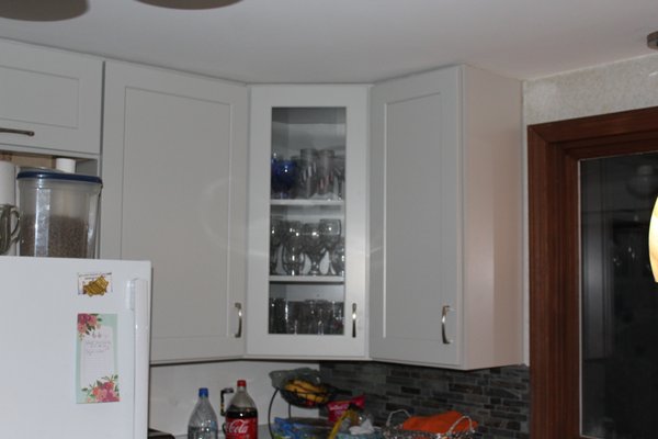 Rob & Sue Project in Marston Mills, MA - The first thing we did on this project was remove a wall between the dining room and the kitchen to let more light into the kitchen. After we removed all the old cabinets we installed new Dove Gray shaker style cabinets and built a peninsula to house then stove with a large drawer cabinet on the right for cooking tools and pots and pans and a pull out spice cabinet on the left and a corner carousel with our adjustable height wire baskets inside. Then we built a base on the other side facing the dining room and installed wall cabinets as base cabinets to add more storage space that is accessible from the dining room. We installed our usual under mount stainless steel insulated sink equipped with cutting board and drying rack both of which are removeable/interchangeable. The quartz countertops were provided by Cape Granite Connection including the small one atop the coffee bar on wheels we built.