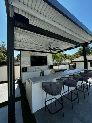 Patio - For this patio project, Power Home Builders completely transformed the outdoor space into a luxurious and functional entertainment area. The remodel included the installation of a sleek, modern patio cover with a slatted roof for shade and ventilation. A fully equipped outdoor kitchen was added, featuring a premium stainless steel BBQ, ample counter space, and a sink for convenience. A custom entertainment wall with a stunning marble slab backdrop houses a large TV and integrated sound system, perfect for outdoor gatherings. The minimalist design, clean lines, and high-quality materials elevate the space, making it a perfect blend of style and practicality.
Call TODAY for a FREE estimate! 833.717.7742 Patio - For this patio project, Power Home Builders completely transformed the outdoor space into a luxurious and functional entertainment area. The remodel included the installation of a sleek, modern patio cover with a slatted roof for shade and ventilation. A fully equipped outdoor kitchen was added, featuring a premium stainless steel BBQ, ample counter space, and a sink for convenience. A custom entertainment wall with a stunning marble slab backdrop houses a large TV and integrated sound system, perfect for outdoor gatherings. The minimalist design, clean lines, and high-quality materials elevate the space, making it a perfect blend of style and practicality.
Call TODAY for a FREE estimate! 833.717.7742
