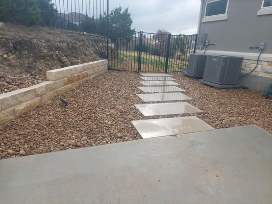 Lueders Stone Walkway & Drainage Improvement in Austin, TX - This project improved backyard access and drainage for a residential property in Austin, TX with a custom Lueders stone walkway. The area was graded and prepared, and drainage was rerouted from the backyard to the street using a 4-inch PVC system to prevent water pooling.
2’ x 4’ Lueders stone slabs were installed over a mortar leveling bed for precise alignment and long-term stability, then finished with gravel infill for proper drainage and a clean, low-maintenance look. The completed walkway provides durable access while improving water flow and overall landscape appearance. Lueders Stone Walkway & Drainage Improvement in Austin, TX - This project improved backyard access and drainage for a residential property in Austin, TX with a custom Lueders stone walkway. The area was graded and prepared, and drainage was rerouted from the backyard to the street using a 4-inch PVC system to prevent water pooling.
2’ x 4’ Lueders stone slabs were installed over a mortar leveling bed for precise alignment and long-term stability, then finished with gravel infill for proper drainage and a clean, low-maintenance look. The completed walkway provides durable access while improving water flow and overall landscape appearance.