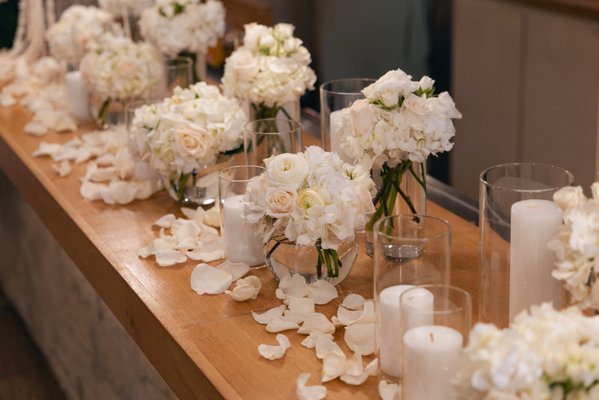 Tina's Baby Shower - We had the pleasure of designing florals for Tina’s baby shower at Zeytuna, featuring an all-white palette for a soft, elegant celebration. The arrangements included white roses, mini spray roses, hydrangea, and ranunculus, creating a timeless and romantic look. Tall floral centerpieces added height and impact to the guest tables, while the bar was styled with smaller vase arrangements, surrounded by glowing candles and delicate white petals. The overall design brought a warm, refined, and serene atmosphere to this special celebration. Tina's Baby Shower - We had the pleasure of designing florals for Tina’s baby shower at Zeytuna, featuring an all-white palette for a soft, elegant celebration. The arrangements included white roses, mini spray roses, hydrangea, and ranunculus, creating a timeless and romantic look. Tall floral centerpieces added height and impact to the guest tables, while the bar was styled with smaller vase arrangements, surrounded by glowing candles and delicate white petals. The overall design brought a warm, refined, and serene atmosphere to this special celebration.