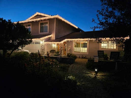 Icicles warm light on roofline - "Beautiful home adorned with warm, festive Christmas lights outlining the roof and porch, creating a welcoming and cheerful holiday atmosphere." Icicles warm light on roofline - "Beautiful home adorned with warm, festive Christmas lights outlining the roof and porch, creating a welcoming and cheerful holiday atmosphere."
