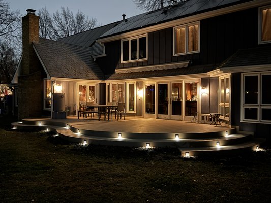 Curved Composite Deck with Low-Voltage Lighting in Overland Park, Kansas - This 700-square-foot composite deck provides an elevated, maintenance-free area that accommodates many people. It facilitates a cohesive connection to the entire backyard while augmenting and enhancing the home's overall appearance. Curved Composite Deck with Low-Voltage Lighting in Overland Park, Kansas - This 700-square-foot composite deck provides an elevated, maintenance-free area that accommodates many people. It facilitates a cohesive connection to the entire backyard while augmenting and enhancing the home's overall appearance.