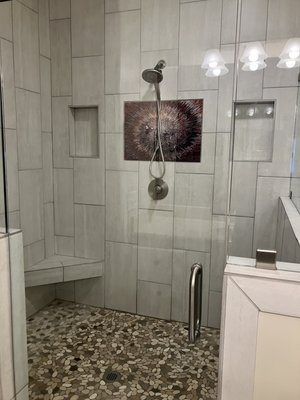 Bathroom Remodel - This was a complete bathroom remodel from a small shower and garden tub to a large walk in shower with some custom accents. We did the same tile throughout the shower walls and bath floors. We added a riverbed tile to the shower base and a custom printed glass as a center piece between the shelves.