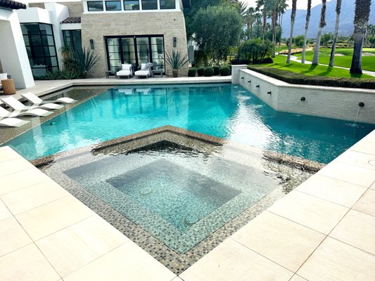 PGA West Modern Pool & Spa Build - There's a reason people buy in PGA West and not somewhere easier. The fairway out back isn't a feature, it's the entire reason the house exists. The Santa Rosa Mountains aren't a view; they're the only acceptable backdrop. And the home behind the pool isn't just architecture, it's a deliberate statement. Stone, steel, glass, and shadow.
A backyard built behind that home has to match the ambition.
This one does.
This PGA West build is a modern statement pool with clean rectilinear geometry, no curves, no compromises. The sunken spa is wrapped corner-to-corner in dark mosaic glass tile that reads bronze in the morning, charcoal at noon, and black at golden hour. A floating sun shelf carries three in-pool loungers under ankle-deep water, the same mosaic glittering underneath like the floor of a hotel pool in Cabo. Along the fairway-facing wall, three matte-black scuppers spill into the main basin in a continuous run, the kind of detail you hear before you see.
The deck is large-format porcelain in a warm travertine tone, laid tight with minimal grout joints so it reads as one continuous surface from the home's sliders to the pool coping. Modern architecture demands modern hardscape, and shortcuts here would have killed the whole composition.
The water sits dark and still. Reflections of the palms, the mountains, the steel-framed windows of the home all land cleanly on the surface, because the entire pool was designed to be a mirror first and a swimming hole second. That's not an accident. That's the brief.
Here's the part most builders won't put in writing: a build at this level is only worth it if the work behind the tile is as good as the tile itself. We've seen homes in PGA West and Madison Club where the plaster looks great on day one and starts failing by year three because the plumbing was rushed, the rebar was light, or the equipment was shaded badly and cooked itself in the first summer.
Desert Luxury Pools designed, permitted, plumbed, gunited, tiled, plastered, and now services this pool year-round. Same crew that set every line of mosaic knows every valve, every controller setting, and every degree of slope on the deck. No handoffs. No "call the warranty department." Just one local team treating it like their own — every service day, every season, year five and beyond.
If you're building behind a modern home in PGA West, Madison Club, The Hideaway, The Quarry, or anywhere along the south end of the valley where the bar is set this high and this is the standard. PGA West Modern Pool & Spa Build - There's a reason people buy in PGA West and not somewhere easier. The fairway out back isn't a feature, it's the entire reason the house exists. The Santa Rosa Mountains aren't a view; they're the only acceptable backdrop. And the home behind the pool isn't just architecture, it's a deliberate statement. Stone, steel, glass, and shadow.
A backyard built behind that home has to match the ambition.
This one does.
This PGA West build is a modern statement pool with clean rectilinear geometry, no curves, no compromises. The sunken spa is wrapped corner-to-corner in dark mosaic glass tile that reads bronze in the morning, charcoal at noon, and black at golden hour. A floating sun shelf carries three in-pool loungers under ankle-deep water, the same mosaic glittering underneath like the floor of a hotel pool in Cabo. Along the fairway-facing wall, three matte-black scuppers spill into the main basin in a continuous run, the kind of detail you hear before you see.
The deck is large-format porcelain in a warm travertine tone, laid tight with minimal grout joints so it reads as one continuous surface from the home's sliders to the pool coping. Modern architecture demands modern hardscape, and shortcuts here would have killed the whole composition.
The water sits dark and still. Reflections of the palms, the mountains, the steel-framed windows of the home all land cleanly on the surface, because the entire pool was designed to be a mirror first and a swimming hole second. That's not an accident. That's the brief.
Here's the part most builders won't put in writing: a build at this level is only worth it if the work behind the tile is as good as the tile itself. We've seen homes in PGA West and Madison Club where the plaster looks great on day one and starts failing by year three because the plumbing was rushed, the rebar was light, or the equipment was shaded badly and cooked itself in the first summer.
Desert Luxury Pools designed, permitted, plumbed, gunited, tiled, plastered, and now services this pool year-round. Same crew that set every line of mosaic knows every valve, every controller setting, and every degree of slope on the deck. No handoffs. No "call the warranty department." Just one local team treating it like their own — every service day, every season, year five and beyond.
If you're building behind a modern home in PGA West, Madison Club, The Hideaway, The Quarry, or anywhere along the south end of the valley where the bar is set this high and this is the standard.