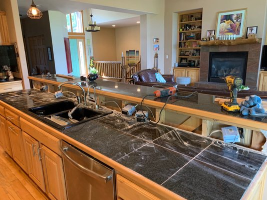 Lower Kitchen Island Countertop - Owner wanted to remove the two height island countertop and replace with one large and lower countertop.  Remove upper counter top.  Cut down
knee wall to proper finished height.  Lower PVC loop drain line.  Move electrical outlet boxes.  Remove garbage disposal, Insta hot, faucet, garbage disposal and sink for later connection.  Repair drywall, tape and mud all intersections, an texture to match.  After no countertop was installed by others, re-install Insta-hot, faucet and garbage disposal