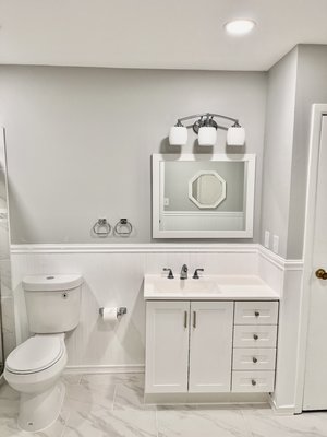 Bathroom remodel - This bathroom remodel showcases a beautiful transformation from an old, enclosed space to an open-concept, spa-like retreat. The new design features a waterproof layout, ideal for long-lasting durability. Modern large-format tiles in a neutral tone cover the floors and shower walls, creating a seamless and expansive look. Bright white wainscoting lines the lower half of the bathroom walls, adding texture and elegance to the space while enhancing the open feel.
A glass sliding shower door adds a sleek touch, allowing light to flow through and making the shower area feel larger. For added safety and accessibility, shower grab bars have been installed, blending function with style. The overall bright white color scheme gives the bathroom a clean, fresh appearance, making it both modern and inviting. Bathroom remodel - This bathroom remodel showcases a beautiful transformation from an old, enclosed space to an open-concept, spa-like retreat. The new design features a waterproof layout, ideal for long-lasting durability. Modern large-format tiles in a neutral tone cover the floors and shower walls, creating a seamless and expansive look. Bright white wainscoting lines the lower half of the bathroom walls, adding texture and elegance to the space while enhancing the open feel.
A glass sliding shower door adds a sleek touch, allowing light to flow through and making the shower area feel larger. For added safety and accessibility, shower grab bars have been installed, blending function with style. The overall bright white color scheme gives the bathroom a clean, fresh appearance, making it both modern and inviting.