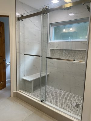 Bathroom Remodel - This bathroom remodel transformed an outdated space into a bright, modern retreat. The project features a custom walk-in shower with frameless glass doors, built-in bench seating, recessed niche shelving, and marble-look tile throughout. A new double vanity with quartz countertops, updated lighting, and premium fixtures completed the renovation. Bathroom Remodel - This bathroom remodel transformed an outdated space into a bright, modern retreat. The project features a custom walk-in shower with frameless glass doors, built-in bench seating, recessed niche shelving, and marble-look tile throughout. A new double vanity with quartz countertops, updated lighting, and premium fixtures completed the renovation.