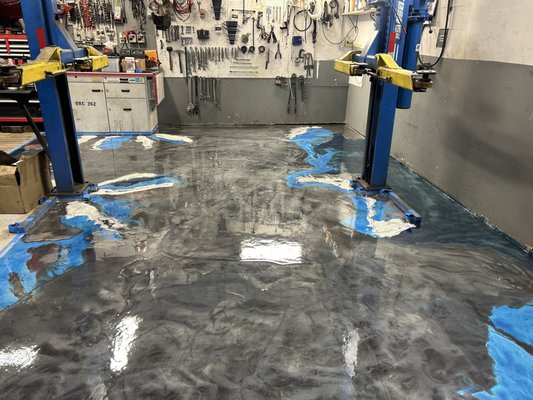 Metallic Marble Epoxy Floor - This garage features a metallic marble epoxy floor, known for its exceptional durability and unique aesthetic. The material combines the resilience of epoxy with a shimmering metallic finish, creating a striking visual effect that mimics natural marble. It's also easy to clean and resistant to stains, making it an ideal choice for high-traffic areas like garages.