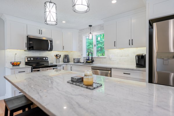 White & Bright Kitchen Renovation in Grafton MA - This homeowner came to us after being recommended by a neighbor who recently completed a project with us. Their kitchen felt dark, tight, and ready for a refresh, but a full renovation wasn’t what they needed. Instead, we focused on a clean, modern facelift that completely changed how the space feels day to day.

We installed new white cabinetry, quartz countertops, and a marble backsplash that brightened the entire room. A large island was added to bring in more storage and a better workflow. We also designed and built custom mudroom cabinets for their entry area to help keep the home organized, and refinished the hardwood floors to finish the look.

The result is a bright, airy kitchen that works for everyday life and feels welcoming the second you walk in. A perfect example of how small layout changes and quality updates can make an older kitchen feel brand new.

A simple facelift can make a huge difference, and this project shows how much function and beauty you can gain without changing the entire layout.