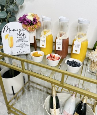Mimosa Bar - Brighten your celebration with our elegant stationary Mimosa bar cart, featuring a stunning array of fresh juices, vibrant fruit garnishes, and top-tier bubbly. Set against a beautifully arranged backdrop, this eye-catching display adds a touch of sophistication and fun to any event, inviting guests to create their perfect blend of refreshment and flavor. Ideal for weddings, brunches, or any special occasion where you want to impress and delight. Contact us today for a free quote to feature a Mimosa bar at your next celebration. Mimosa Bar - Brighten your celebration with our elegant stationary Mimosa bar cart, featuring a stunning array of fresh juices, vibrant fruit garnishes, and top-tier bubbly. Set against a beautifully arranged backdrop, this eye-catching display adds a touch of sophistication and fun to any event, inviting guests to create their perfect blend of refreshment and flavor. Ideal for weddings, brunches, or any special occasion where you want to impress and delight. Contact us today for a free quote to feature a Mimosa bar at your next celebration.