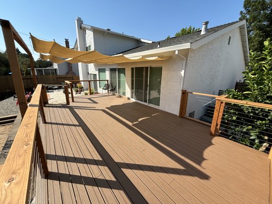 Roseville Trex deck - 2024 - Last year, we built a Trex deck in Roseville, transforming a backyard into a modern outdoor retreat. Using durable Trex composite decking, we created a low-maintenance deck that complements the home’s exterior, with a frame of pressure-treated lumber. The deck features a spacious main area and two stepped sections with gates to keep the dogs in. A standout addition is the cable guardrail, with stainless-steel cables tensioned between wooden posts, ensuring safety and an open view. A retractable shade canopy adds versatility for sun or shade.