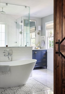 Island Road - n this stunning bathroom renovation, we blend modern elegance with timeless sophistication, drawing from the existing layout and preserving the room's abundant natural light by retaining its stunning windows. The focal point of the space is a luxurious freestanding bathtub positioned prominently in front of the shower, creating a centerpiece of luxury and relaxation surrounded by a combination of cement tiles and marble that exudes opulence. Adjacent to the tub, a spacious walk-in shower features glass walls and polished nickel fixtures, complemented by an intricate drain design and carefully chosen floor tiles, elevating it to a work of art. The vanity area, with built-in cabinetry in a chic muted blue hue, marble countertop, subway tile backsplash, wainscoting, and custom makeup area, adds both style and functionality, while warm ambient lighting enhances the inviting atmosphere, resulting in an unparalleled retreat within the home. Island Road - n this stunning bathroom renovation, we blend modern elegance with timeless sophistication, drawing from the existing layout and preserving the room's abundant natural light by retaining its stunning windows. The focal point of the space is a luxurious freestanding bathtub positioned prominently in front of the shower, creating a centerpiece of luxury and relaxation surrounded by a combination of cement tiles and marble that exudes opulence. Adjacent to the tub, a spacious walk-in shower features glass walls and polished nickel fixtures, complemented by an intricate drain design and carefully chosen floor tiles, elevating it to a work of art. The vanity area, with built-in cabinetry in a chic muted blue hue, marble countertop, subway tile backsplash, wainscoting, and custom makeup area, adds both style and functionality, while warm ambient lighting enhances the inviting atmosphere, resulting in an unparalleled retreat within the home.