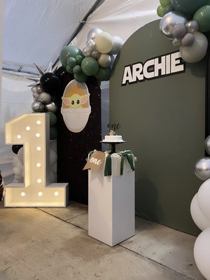 One With the Force - This was a custom backdrop design for a "Stars Wars" theme 1st birthday party.
Our customer gave us the color scheme and "Baby Yoda" graphic she wanted to use, we did the rest. Customizing all the details and making her event magical!