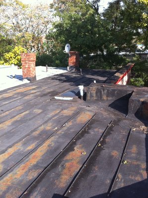 Resurfacing a weathered metal flat roof with fibered aluminum coating - This photo shows the old metal flat roof in its weathered condition before resurfacing. Years of exposure have caused visible rust, fading, and surface wear, leaving the roof vulnerable to leaks and further deterioration. The seams and panels show signs of aging, and the lack of reflective protection has allowed heat and moisture to take a toll on the metal Resurfacing a weathered metal flat roof with fibered aluminum coating - This photo shows the old metal flat roof in its weathered condition before resurfacing. Years of exposure have caused visible rust, fading, and surface wear, leaving the roof vulnerable to leaks and further deterioration. The seams and panels show signs of aging, and the lack of reflective protection has allowed heat and moisture to take a toll on the metal