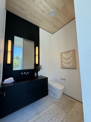 Entry Powder Room - Transform your powder room with a chic remodel featuring bold black slabs that create a striking backdrop. At the entrance, a sleek Toto toilet combines modern convenience with elegance. A custom-built counter with a continues slab integrated sink offering a seamless and sophisticated look.
The design emphasizes clean lines and minimalist aesthetics, enhanced by warm lighting that showcases the rich textures. This powder room impresses guests and adds a touch of luxury to your home, creating an inviting and elegant atmosphere. Entry Powder Room - Transform your powder room with a chic remodel featuring bold black slabs that create a striking backdrop. At the entrance, a sleek Toto toilet combines modern convenience with elegance. A custom-built counter with a continues slab integrated sink offering a seamless and sophisticated look.
The design emphasizes clean lines and minimalist aesthetics, enhanced by warm lighting that showcases the rich textures. This powder room impresses guests and adds a touch of luxury to your home, creating an inviting and elegant atmosphere.