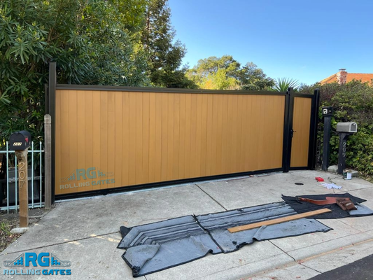 Rolling Gate & Pedestrian Gate - Custom Wood-Filled Sliding Gate framed in durable, powder-coated steel. This design pairs natural wood’s rustic appeal with a sleek, powder-coated frame for a striking balance of style and strength. The sliding gate offers smooth, space-saving functionality, while the matching pedestrian gate provides easy access without sacrificing security. Together, they create a cohesive, inviting entrance that enhances both the look and value of your home. Rolling Gate & Pedestrian Gate - Custom Wood-Filled Sliding Gate framed in durable, powder-coated steel. This design pairs natural wood’s rustic appeal with a sleek, powder-coated frame for a striking balance of style and strength. The sliding gate offers smooth, space-saving functionality, while the matching pedestrian gate provides easy access without sacrificing security. Together, they create a cohesive, inviting entrance that enhances both the look and value of your home.