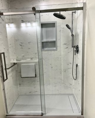 Bathroom remodel - This bathroom remodel we removed an old outdated jet tub/shower combo. We replaced it with a sleek modern walk in shower with glass barn doors. The owners requested a fold up shower chair and hand rails to accommodate theirs needs!