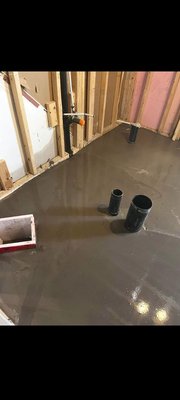 Under-slab drain line installation – 2019 - Drain lines set in a basement slab before the pour. Black ABS drain pipe, PVC cleanouts and a vent were placed in trenches, then capped stubs were left standing through the new concrete.