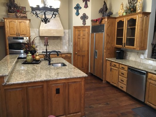 Flower Mound Kitchen Cabinet Upgrade - Kitchen cabinet painting is one of the most popular projects we offer.  Here we see the before, during, and after pictures of the process.  This type of project requires a minimum of three days and some larger projects can take four to five days to complete.  We have had some that require more than five days but that is not the norm.
Typically, the masking process takes about one full day at the start of the project.  Primer application is the next step followed by hand sanding.  Finally, two top coats of enamel are applied using a spray machine to achieve a factory-smooth surface finish.