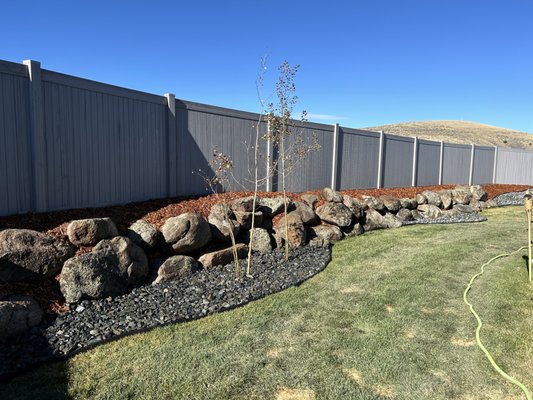 Backyard Paradise - This project required the use of boulders to shift a hill to align with the property line.  This allowed the installation of a fence as well as a rock and mulch landscape to set the stage.