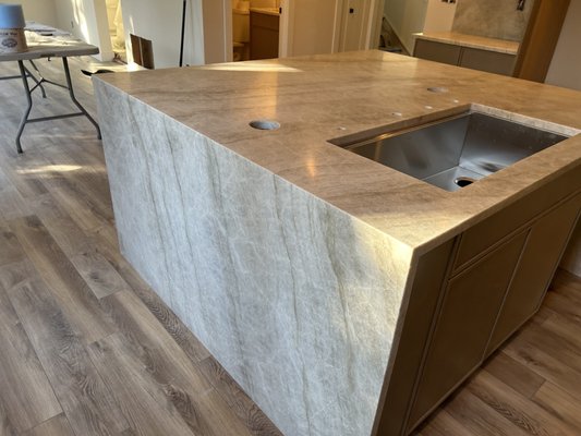 Taj Mahal Quartzite Countertop - We recently had the joy of working on a full-house remodel where we helped the homeowner bring their dream kitchen to life with this stunning Taj Mahal quartzite countertop. 🌟
From concept to creation, here's the story of how this masterpiece came together:
1️⃣ Waterfall Island: The centerpiece of this kitchen is undoubtedly the breathtaking waterfall island. Its seamless design flows effortlessly, creating a luxurious and inviting focal point. Perfect for family gatherings or hosting friends!
2️⃣ Pop-Up Outlets: Hidden yet handy, the pop-up outlets are a modern marvel, making it easier than ever to keep all your gadgets charged while maintaining a clean and uncluttered look.
3️⃣ Ledge Behind the Range: We added a practical and stylish ledge behind the range. It’s the ideal spot for culinary essentials, keeping everything within reach while you cook up your favorite recipes.
4️⃣ Full-Height Backsplash: Extending the elegant Taj Mahal quartzite up the wall adds a cohesive and high-end touch, tying the whole space together and offering a durable, easy-to-clean surface.
This remodel wasn’t just about the aesthetics – it’s about making the kitchen a place where memories are made, meals are shared, and life happens. ✨🏡 Whether you’re a seasoned chef or love the idea of a chic, functional kitchen, this space has it all. Taj Mahal Quartzite Countertop - We recently had the joy of working on a full-house remodel where we helped the homeowner bring their dream kitchen to life with this stunning Taj Mahal quartzite countertop. 🌟
From concept to creation, here's the story of how this masterpiece came together:
1️⃣ Waterfall Island: The centerpiece of this kitchen is undoubtedly the breathtaking waterfall island. Its seamless design flows effortlessly, creating a luxurious and inviting focal point. Perfect for family gatherings or hosting friends!
2️⃣ Pop-Up Outlets: Hidden yet handy, the pop-up outlets are a modern marvel, making it easier than ever to keep all your gadgets charged while maintaining a clean and uncluttered look.
3️⃣ Ledge Behind the Range: We added a practical and stylish ledge behind the range. It’s the ideal spot for culinary essentials, keeping everything within reach while you cook up your favorite recipes.
4️⃣ Full-Height Backsplash: Extending the elegant Taj Mahal quartzite up the wall adds a cohesive and high-end touch, tying the whole space together and offering a durable, easy-to-clean surface.
This remodel wasn’t just about the aesthetics – it’s about making the kitchen a place where memories are made, meals are shared, and life happens. ✨🏡 Whether you’re a seasoned chef or love the idea of a chic, functional kitchen, this space has it all.