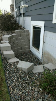 Window well - Updated window well area with custom retaining wall and decorative rock.