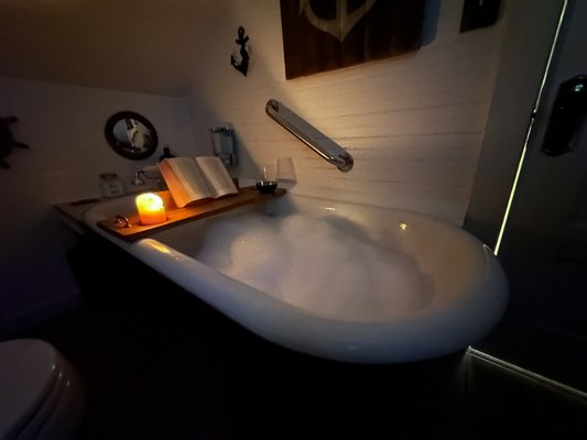 Captain's Cottage - Built in 1926, this antique filled nautical themed cottage is filled with history and quirky charm. Many items and portraits are from the original Sea Captain who built these cottages. Grab yourself a glass of wine, a good book, a candle and come soak in a tub filled with Lavender bubble bath. This large antique claw foot soaking tub is waiting for you to come relax in our uniquely themed Captain’s Cottage. This studio, with separate bath and full kitchen, is our second floor cottage. It is relaxing and perfect for those wanting a romantic or unique themed getaway. It is decorated in a unique nautical theme and surrounded by antiques and history.
An artistic mural painting of a old sailing ship abodes the kitchen fridge and wall, as well as the original 1926 bead-board ceilings and architectural designs from a by-gone era. Pets are allowed.
Adults only in this cottage due to antique items.
(Handheld shower only in tub, no standup shower) Captain's Cottage - Built in 1926, this antique filled nautical themed cottage is filled with history and quirky charm. Many items and portraits are from the original Sea Captain who built these cottages. Grab yourself a glass of wine, a good book, a candle and come soak in a tub filled with Lavender bubble bath. This large antique claw foot soaking tub is waiting for you to come relax in our uniquely themed Captain’s Cottage. This studio, with separate bath and full kitchen, is our second floor cottage. It is relaxing and perfect for those wanting a romantic or unique themed getaway. It is decorated in a unique nautical theme and surrounded by antiques and history.
An artistic mural painting of a old sailing ship abodes the kitchen fridge and wall, as well as the original 1926 bead-board ceilings and architectural designs from a by-gone era. Pets are allowed.
Adults only in this cottage due to antique items.
(Handheld shower only in tub, no standup shower)