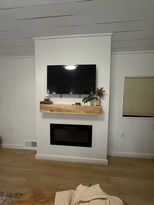 Modern TV Wall with Floating Wood Mantel & Electric Fireplace - This project focused on creating a clean and modern TV wall that blends warmth and functionality.
We mounted the TV at an optimal viewing height, installed a custom floating wood mantel for visual balance, and integrated a sleek electric fireplace to complete the feature wall.
The result is a minimalist media wall that serves as a focal point of the living space while maintaining a calm, contemporary aesthetic. Modern TV Wall with Floating Wood Mantel & Electric Fireplace - This project focused on creating a clean and modern TV wall that blends warmth and functionality.
We mounted the TV at an optimal viewing height, installed a custom floating wood mantel for visual balance, and integrated a sleek electric fireplace to complete the feature wall.
The result is a minimalist media wall that serves as a focal point of the living space while maintaining a calm, contemporary aesthetic.
