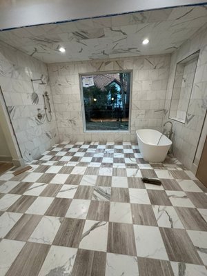 Another Luxurious Bathroom Remodel - This project showcases our ability to create truly transformative, high-end spaces. We designed this bathroom as an open-concept, doorless wet room, providing a spacious and seamless flow between the shower and bath.

​The tile work is the star of the show, featuring a masterful blend of textures and patterns. The walls and ceiling are clad in sleek, large-format marble-look porcelain, while the floor presents a striking, custom checkered pattern using both the marble-look tile and a complementary wood-grain tile for visual interest and sophisticated contrast.
​A luxurious freestanding tub is perfectly positioned in front of a massive picture window, flooding the room with natural light and a stunning view of the outdoors. 
This project is a testament to our skill in combining bold design with flawless execution, creating a private, spa-like sanctuary for the homeowner.