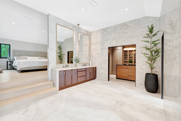 Master & Bath Remodel In Orange - This stunning remodel in Orange, CA showcases a luxurious spa-inspired primary suite and a sleek modern fireplace feature, designed to feel like a boutique resort at home.
The new bathroom is wrapped in Taj Mahal quartzite slabs, creating a seamless, high-end look from floor to ceiling. A generous walk-in shower features multiple shower heads, a linear drain, built‑in niches, and recessed LED lighting that highlights the architectural lines of the ceiling. A freestanding tub, floating vanity cabinetry, and full-height mirrors with integrated sconces add to the spa atmosphere while providing ample storage and task lighting.
Expansive glass doors and windows open the space to the outdoors, bringing in natural light and framing views of the surrounding landscape. Warm wood tones in the custom vanities and accent pieces balance the soft neutrals of the tile, giving the room both warmth and sophistication.
In the adjacent master bedroom, a contemporary fireplace wall becomes a dramatic focal point. Vertical New Tech wood, integrated lighting, and a sleek linear fireplace are paired with a modern art niche above, creating a clean, gallery-like presentation.
From framing and layout changes to the careful selection of finishes and lighting, this project demonstrates detailed craftsmanship and thoughtful design, transforming a dated interior into a bright, modern retreat ideal for everyday living and entertaining. Master & Bath Remodel In Orange - This stunning remodel in Orange, CA showcases a luxurious spa-inspired primary suite and a sleek modern fireplace feature, designed to feel like a boutique resort at home.
The new bathroom is wrapped in Taj Mahal quartzite slabs, creating a seamless, high-end look from floor to ceiling. A generous walk-in shower features multiple shower heads, a linear drain, built‑in niches, and recessed LED lighting that highlights the architectural lines of the ceiling. A freestanding tub, floating vanity cabinetry, and full-height mirrors with integrated sconces add to the spa atmosphere while providing ample storage and task lighting.
Expansive glass doors and windows open the space to the outdoors, bringing in natural light and framing views of the surrounding landscape. Warm wood tones in the custom vanities and accent pieces balance the soft neutrals of the tile, giving the room both warmth and sophistication.
In the adjacent master bedroom, a contemporary fireplace wall becomes a dramatic focal point. Vertical New Tech wood, integrated lighting, and a sleek linear fireplace are paired with a modern art niche above, creating a clean, gallery-like presentation.
From framing and layout changes to the careful selection of finishes and lighting, this project demonstrates detailed craftsmanship and thoughtful design, transforming a dated interior into a bright, modern retreat ideal for everyday living and entertaining.