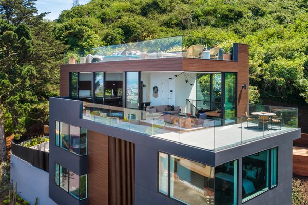 Twin Peaks Home - This home is nestled at the foot of the hill on a unique detached triangular lot in Twin Peaks. While keeping most of the original 1940’s structure intact and adding one additional level with wraparound terraces and a roof garden to capture the panoramic views, this custom home offers 5,015 SF of indoor-outdoor living space for a young, growing family. The dynamic relationship between the natural environment and architecture begins at the front entry as the outdoor lighting, pavers and rock garden continue to the indoor foyer. On the second floor, the family room opens up to a curved, south facing outdoor yard. The refined interior stair connecting all floors floats alongside a multi-story window wall that captures the wild green hillside. The façade utilizes durable, metal siding and slats to help frame and screen views of the natural environment while also responding to the floor plan within. Designed by Winder Gibson Architects, in close collaboration with the owner and Interior Designer, Derek Dean and with the GC, The Toboni Group, the house juxtaposes refined architectural details with natural elements to create a harmonious flow between indoor and outdoor, far and near views, dark and light, hard and soft materials. Twin Peaks Home - This home is nestled at the foot of the hill on a unique detached triangular lot in Twin Peaks. While keeping most of the original 1940’s structure intact and adding one additional level with wraparound terraces and a roof garden to capture the panoramic views, this custom home offers 5,015 SF of indoor-outdoor living space for a young, growing family. The dynamic relationship between the natural environment and architecture begins at the front entry as the outdoor lighting, pavers and rock garden continue to the indoor foyer. On the second floor, the family room opens up to a curved, south facing outdoor yard. The refined interior stair connecting all floors floats alongside a multi-story window wall that captures the wild green hillside. The façade utilizes durable, metal siding and slats to help frame and screen views of the natural environment while also responding to the floor plan within. Designed by Winder Gibson Architects, in close collaboration with the owner and Interior Designer, Derek Dean and with the GC, The Toboni Group, the house juxtaposes refined architectural details with natural elements to create a harmonious flow between indoor and outdoor, far and near views, dark and light, hard and soft materials.