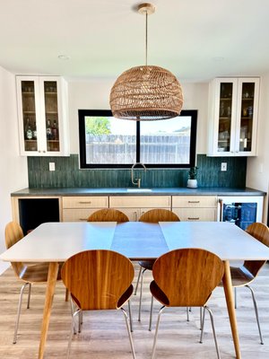 Home Remodel UTC - This completely remodeled kitchen showcases a perfect blend of modern design, quality finishes, and clever functionality, all achieved while respecting the original home design and budget constraints.
The heart of the space is the oversized center island, featuring a dramatic waterfall edge in white, subtly veined quartz, providing ample workspace and seating for four. This focal point is beautifully illuminated by three ribbed glass globe pendants with brass accents, which cast a striking, radial light pattern across the ceiling.
Key Design Highlights:
Cabinetry: Custom-look, light natural oak-style cabinetry provides a clean, contemporary aesthetic and offers generous storage, including a floor-to-ceiling pantry/cabinet run.
Appliances: The kitchen features sleek, modern appliances, including a striking white and copper/brass accent refrigerator that seamlessly integrates with the overall warm color palette.
Backsplash: A bold yet sophisticated dark green, vertical stacked-tile backsplash adds a rich layer of color and texture, providing a stunning contrast to the light wood and white countertops.
Flooring: Durable and attractive light wood-look plank flooring runs throughout, unifying the space and complementing the natural tone of the cabinets.
Fixtures: Brushed brass/gold finishes on the lighting, cabinet hardware, and high-arc faucet introduce a touch of warmth and luxury.
The design successfully maximizes the home's layout, creating a bright, open, and highly functional space ideal for both everyday living and entertaining. Home Remodel UTC - This completely remodeled kitchen showcases a perfect blend of modern design, quality finishes, and clever functionality, all achieved while respecting the original home design and budget constraints.
The heart of the space is the oversized center island, featuring a dramatic waterfall edge in white, subtly veined quartz, providing ample workspace and seating for four. This focal point is beautifully illuminated by three ribbed glass globe pendants with brass accents, which cast a striking, radial light pattern across the ceiling.
Key Design Highlights:
Cabinetry: Custom-look, light natural oak-style cabinetry provides a clean, contemporary aesthetic and offers generous storage, including a floor-to-ceiling pantry/cabinet run.
Appliances: The kitchen features sleek, modern appliances, including a striking white and copper/brass accent refrigerator that seamlessly integrates with the overall warm color palette.
Backsplash: A bold yet sophisticated dark green, vertical stacked-tile backsplash adds a rich layer of color and texture, providing a stunning contrast to the light wood and white countertops.
Flooring: Durable and attractive light wood-look plank flooring runs throughout, unifying the space and complementing the natural tone of the cabinets.
Fixtures: Brushed brass/gold finishes on the lighting, cabinet hardware, and high-arc faucet introduce a touch of warmth and luxury.
The design successfully maximizes the home's layout, creating a bright, open, and highly functional space ideal for both everyday living and entertaining.